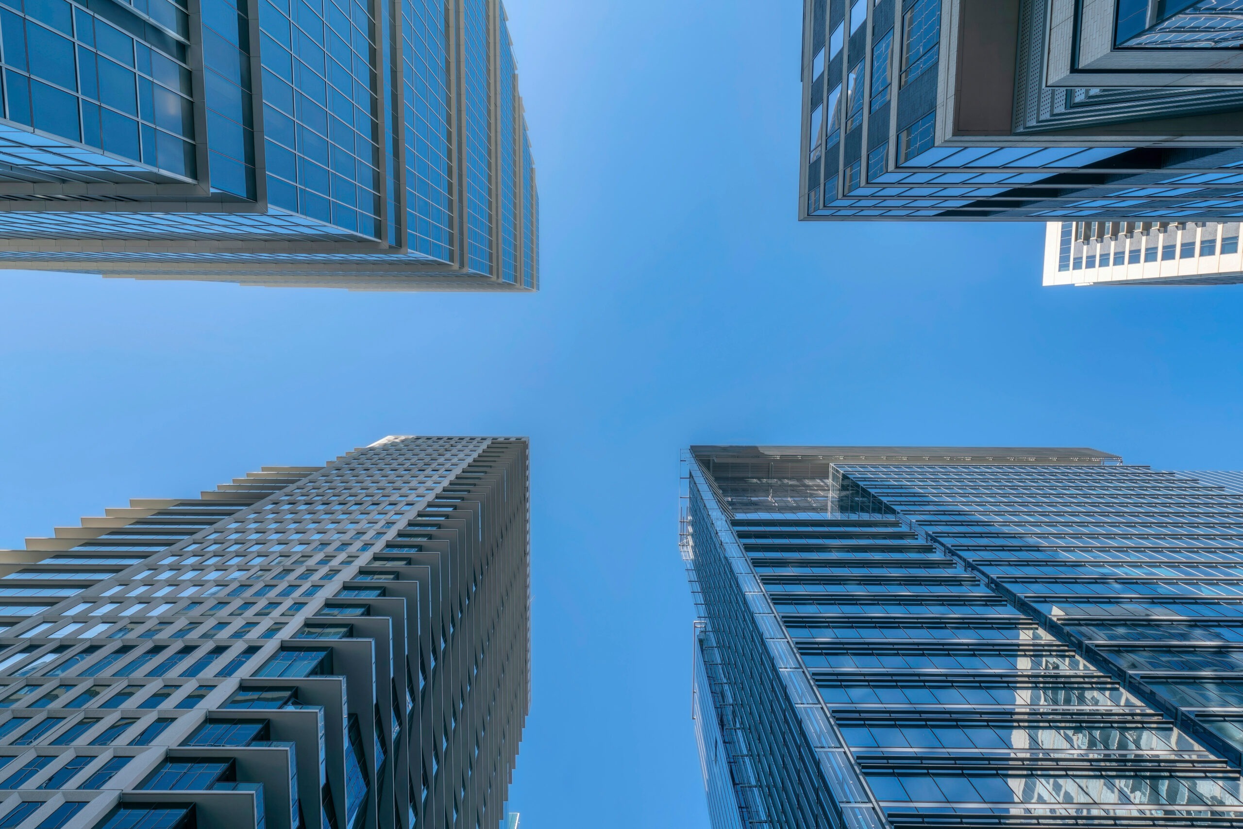 Austin, Texas- Four high-rise buildings with glass exterior against the blue sky backgound. View of buildings from below with reflective glass walls.